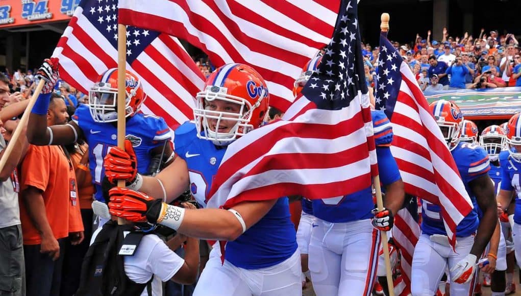 Florida Gators running on field during pre-game in The Swamp, carrying American flags 11-23-2013