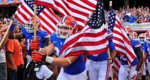 Florida Gators running on field during pre-game in The Swamp, carrying American flags 11-23-2013