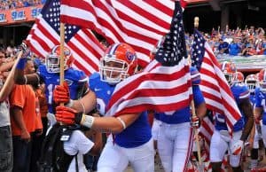 Florida Gators running on field during pre-game in The Swamp, carrying American flags 11-23-2013