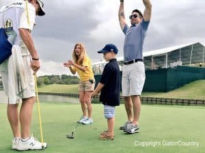 Jake Owen celebrates a putt by a young boy on the spectator hole at the Tim Tebow Golf Classic/GatorCountry photo by Kassidy Hill