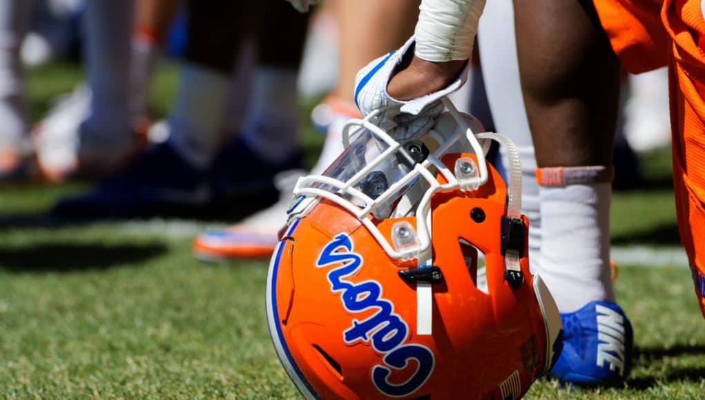 A player rests on his helmet while Dan Mullen addresses the Florida Gators football team after a spring practice- Florida Gators football- 1280x853